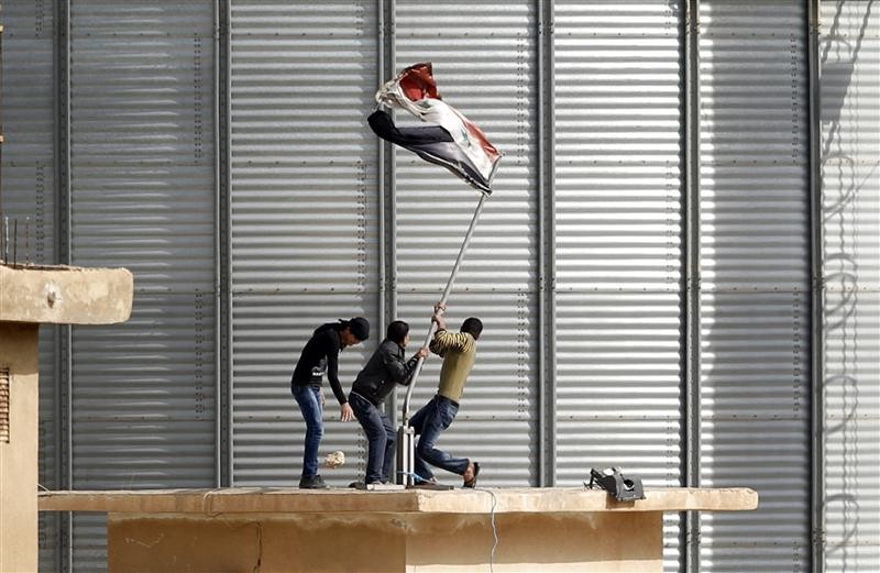 Powstańcy zdejmujący flagę Syrii z posterunku granicznego w Ras al-Ayn - fot. Reuters