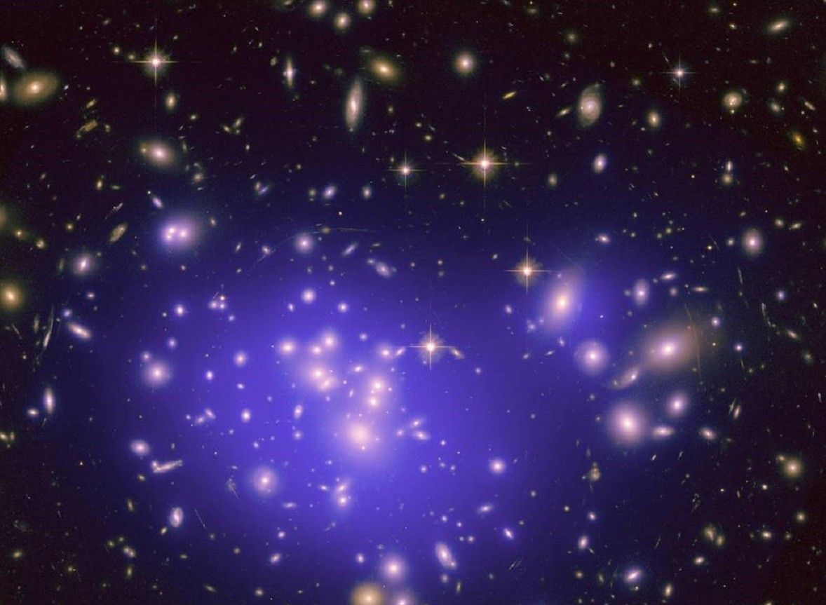 Obraz z teleskopu Hubble'a przedstawiający widok pola galaktyk zniekształcony pod wpływem soczewkowania grawitacyjnego - prawdopodobnie ciemnej materii. Fot. NASA / nasa.gov
