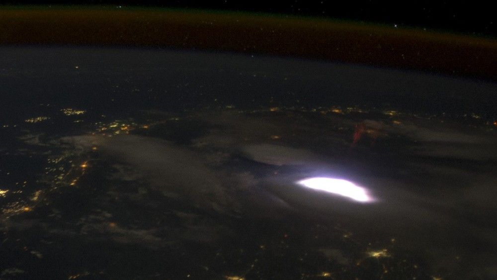 Zdjęcie wykonane w 2012 roku z pokładu Międzynarodowej Stacji Kosmicznej. Nad widoczną na zdjęciu, rozświetlającą chmury błyskawicą, widać charakterystycznego czerwonego ‘duszka’ (sprite). Fot. NASA