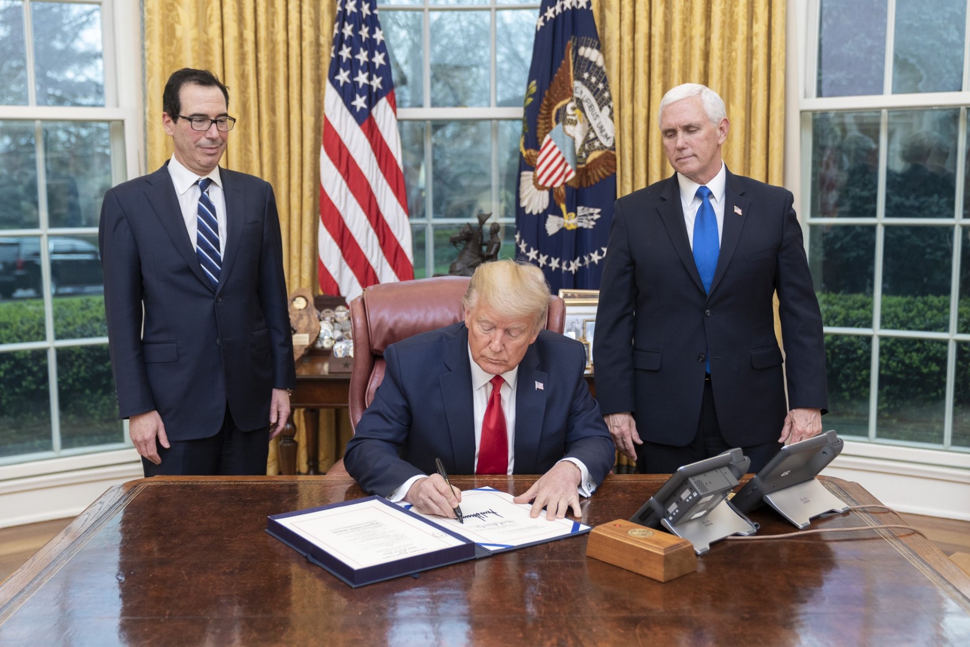 Donald Trump Prezydent USA oraz Steve Mnuchin  (Sekretarz Skarbu - z lewej) i Mike Pence, Wiceprezydent USA podczas podpisywania aktów prawnych mających ułatwić walkę z koronawirusem w USA. Fot. Twitter/Biały Dom