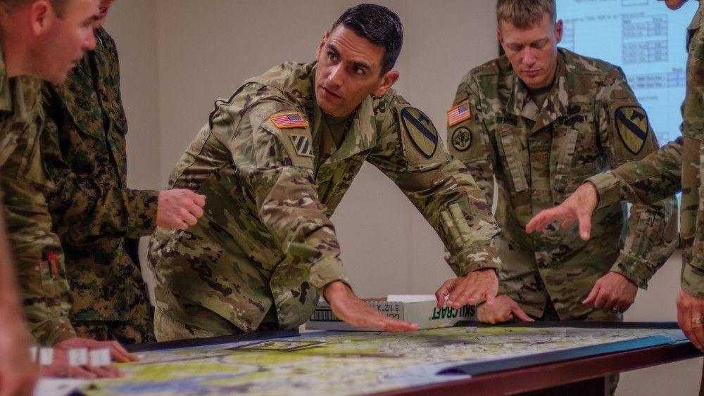 Maj. Lazaro Oliva, Jr. pokazuje potencjalne skutki decyzji taktycznej innym planistom 1 Dywizji Kawalerii podczas gry w Tactical Wargaming Analysis Model. Fot. U.S. Army, Maj. Joseph Payton.