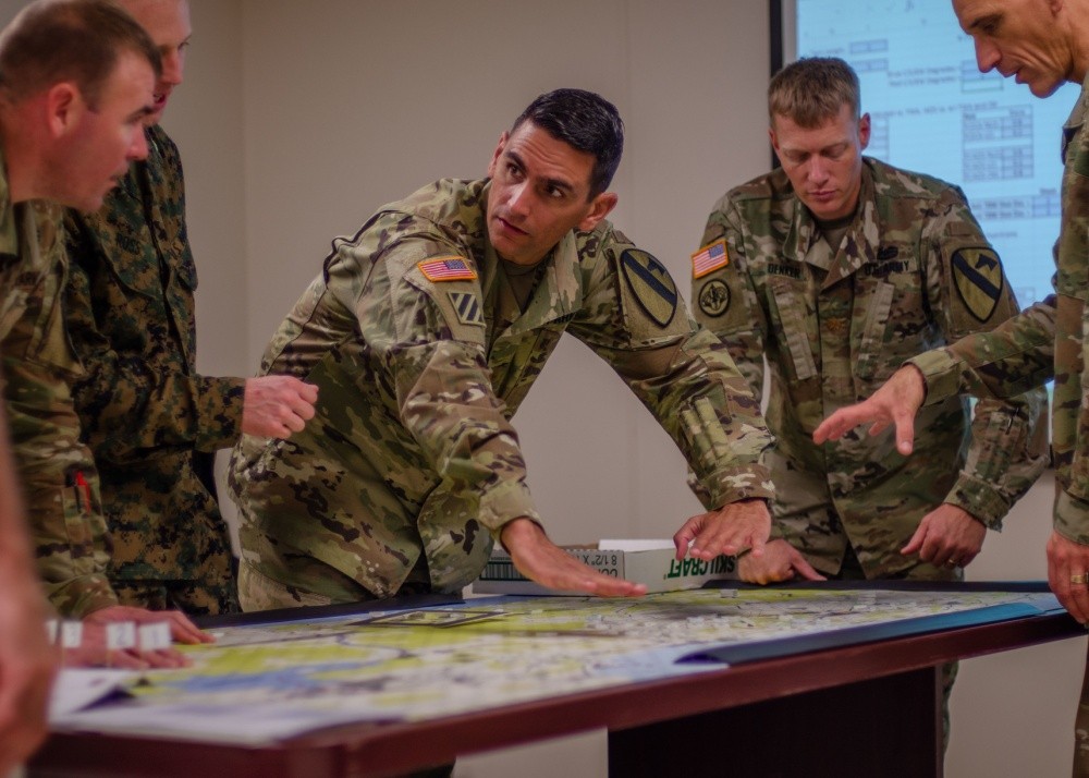 Maj. Lazaro Oliva, Jr. pokazuje potencjalne skutki decyzji taktycznej innym planistom 1 Dywizji Kawalerii podczas gry w Tactical Wargaming Analysis Model. Fot. U.S. Army, Maj. Joseph Payton.