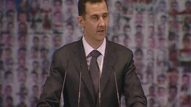 Prezydent al-Asad przemawia na tle flagi  utworzonej ze zdjęć twarzy - Fot. Reuters.