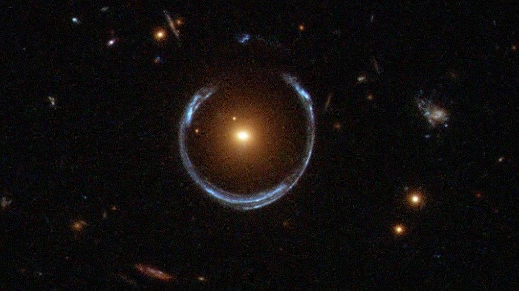 Obraz galaktyki LRG 3-757 – wyraźnie widoczny pierścień Einsteina w kształcie podkowy to najbardziej charakterystyczny przejaw soczewkowania grawitacyjnego i powstającego w jego wyniku ugięcia i rozciągnięcia obserwowanego obrazu. Fot. ESA/Hubble & NASA