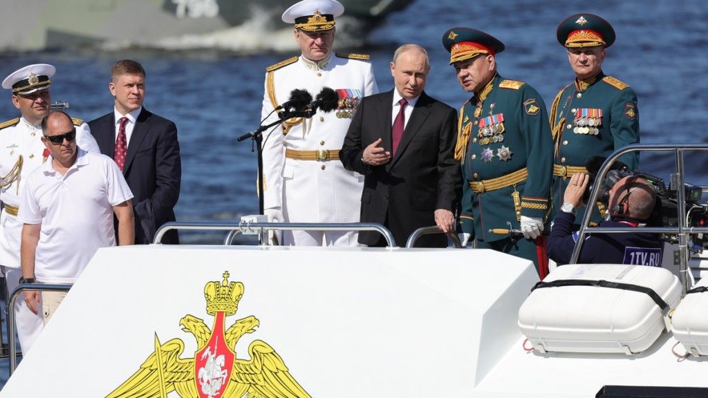 Rosyjski prezydent Putin i minister obrony Szojgu, najwyraźniej w dobrych humorach, przeprowadzają inspekcję zacumowanych okrętów na Newie.