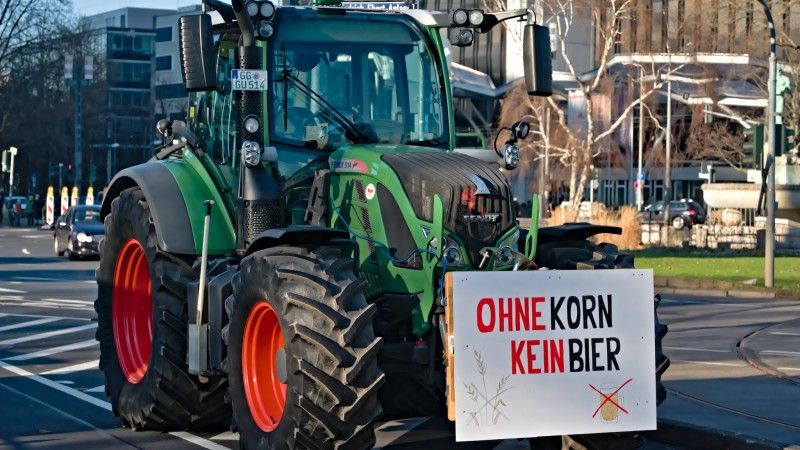 Traktor z wyieszonym z przodu transparentem z napisem ohne korn kein bier – nie ma piwa bez zboża