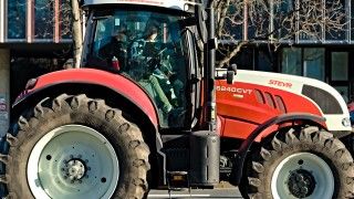 Kobieta siedząca w kabinie biało-czerwonego ciągnika