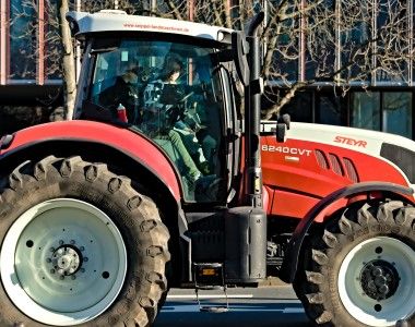 Kobieta siedząca w kabinie biało-czerwonego ciągnika