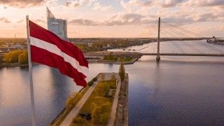 Widok na rzekę Dźwinę i budynki w Rydze, na pierwszym planie flaga Łotwy