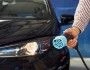 Mężczyzna trzyma wtyczkę do ładowania samochodu elektrycznego. W tyle czarny samochód