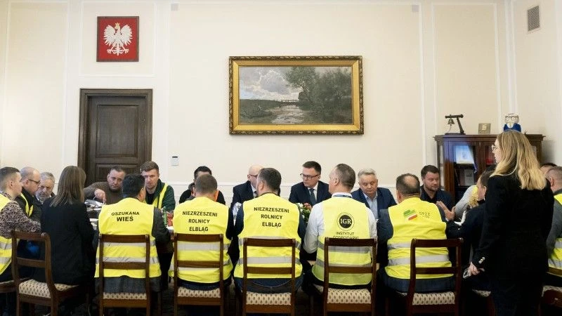 Szymon Hołownia siedzący przy stole z protestującymi rolnikami