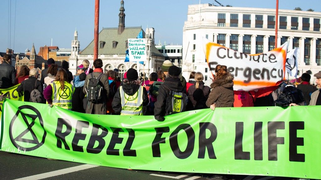 Grupa aktywistów na ulicy trzyma zielony transparent z napisem: Rebel for life