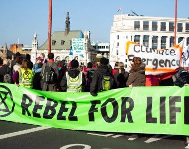 Grupa aktywistów na ulicy trzyma zielony transparent z napisem: Rebel for life