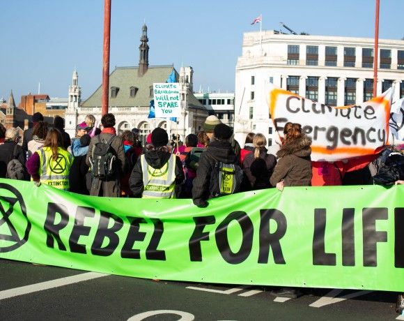 Grupa aktywistów na ulicy trzyma zielony transparent z napisem: Rebel for life