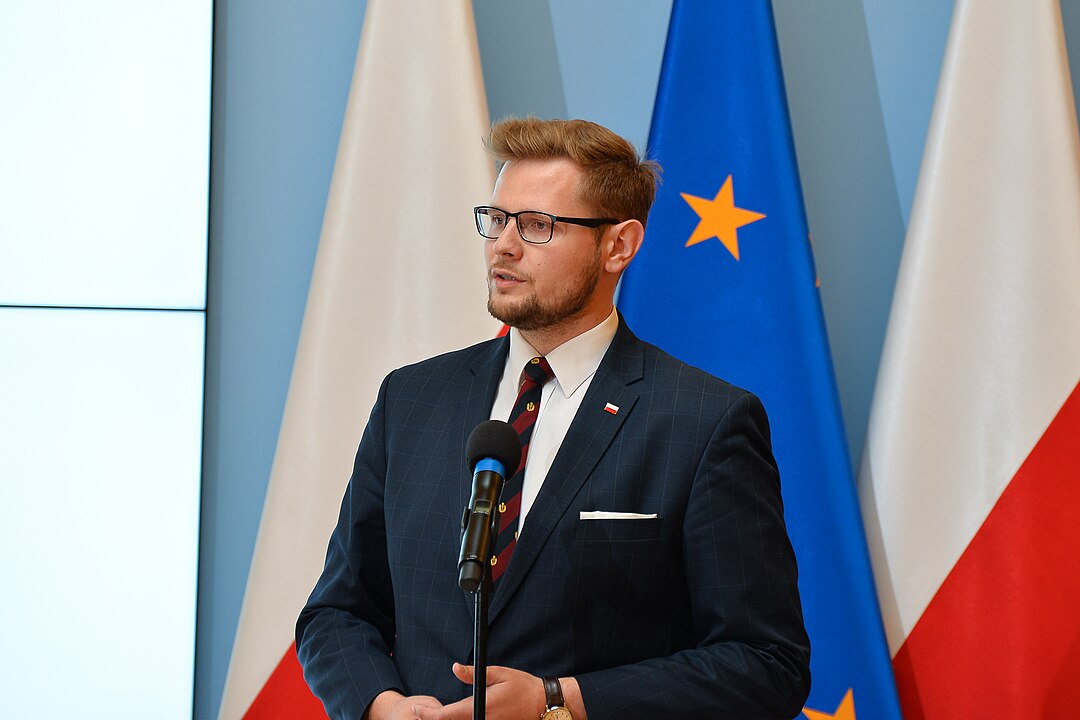Michał Woś przed komisją śledczą ws. Pegasusa. W tle przeszukanie pokoju hotelowego