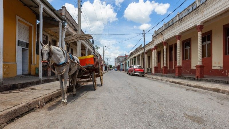 Uliczka w małym kubańskim mieście. Zaparkowany samochód i wóz z koniem