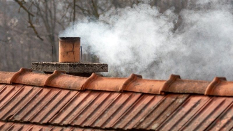 Komin na dachu, z którego wydobywa się dym