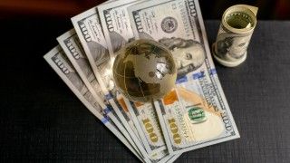 Kryształowa kula ziemska położona na pliku dolarów