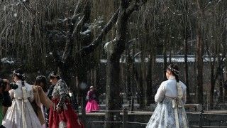 Kobiety w tradycyjnych koreańskich strojach podczas opadu śniegu w parku w Seulu
