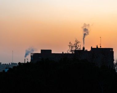 miejski krajobraz, dym wydobywający się z kominów domów na tle zachodzącego słońca