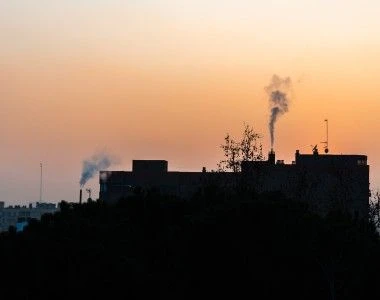 miejski krajobraz, dym wydobywający się z kominów domów na tle zachodzącego słońca