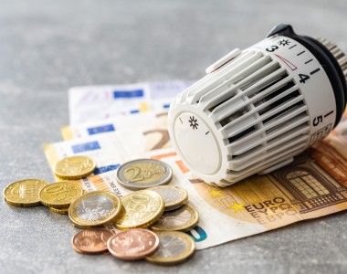 Głowica termostatyczna leży na rozrzuconych banknotach euro