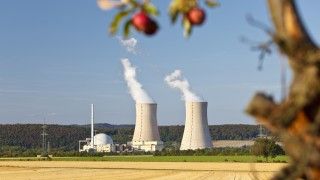 Reaktory jądrowe po środku pola i jabłka zwisające z drzewa