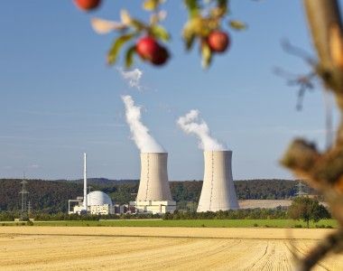 Reaktory jądrowe po środku pola i jabłka zwisające z drzewa