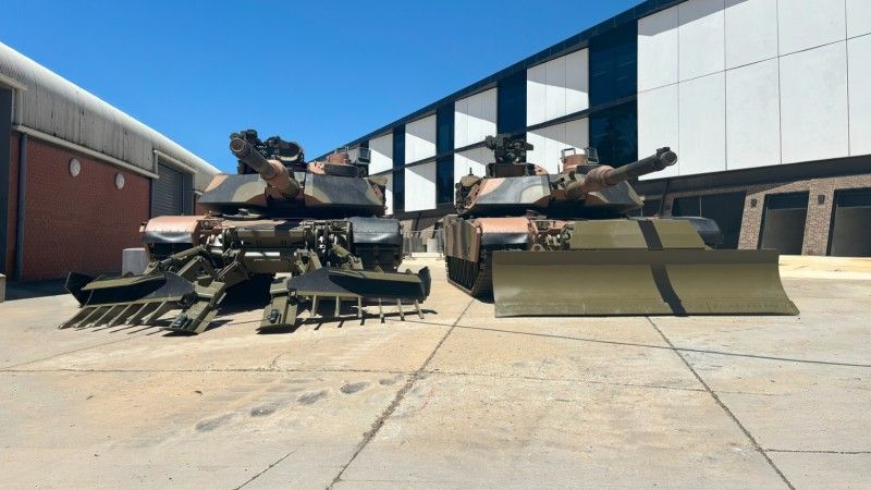 Dwa australijskie czołgi M1A2SEPv3 wyposażone w adaptery SLICE, wóz po prawej wyposażony w lemiesz spycharki, zaś po lewej w pług przeciwminowy TWMP (Track Width Mine Plough).