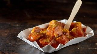Kawałki kiełbaski currywurst na papierowym talerzyku