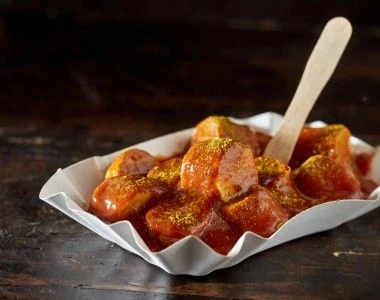 Kawałki kiełbaski currywurst na papierowym talerzyku