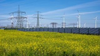 Panele fotowoltaiczne i wiatraki na tle łąki