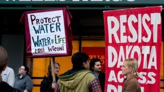 Ludzie protestują z banerami przeciw rurociągowi Dakota Access.