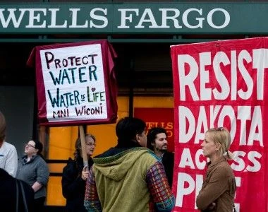 Ludzie protestują z banerami przeciw rurociągowi Dakota Access.