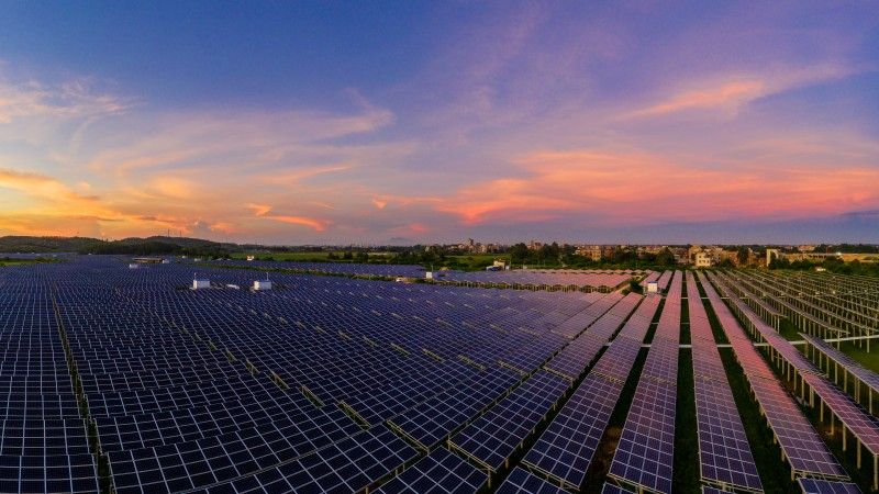 Widok na farmę fotowoltaiczną o zachodzie słońca.
