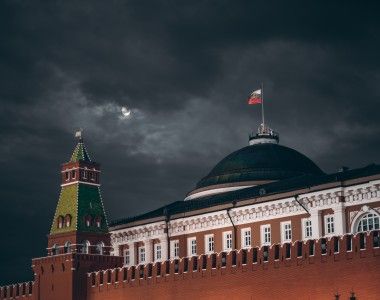 Widok na kopułę Pałacu Senackiego na Kremlu nocą z powiewającą rosyjską flagą.