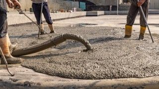 Robotnicy wylewający mokry beton.