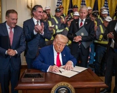 Prezydent USA podpisujący dekret w sprawie węgla w otoczeniu administracji i górników.