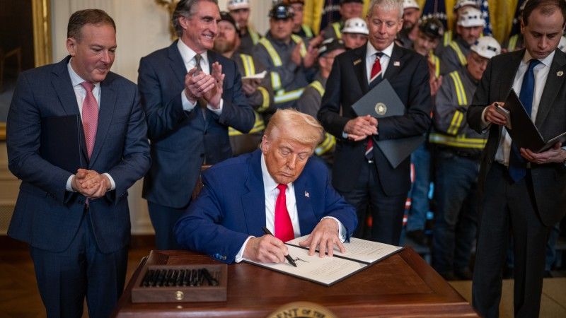 Prezydent USA podpisujący dekret w sprawie węgla w otoczeniu administracji i górników.