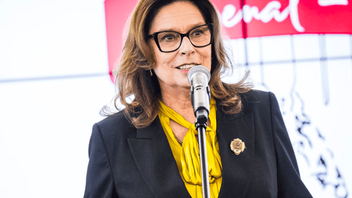 Polityczka przemawia do mikrofonu na tle biało-czerwonego baneru z napisem senat