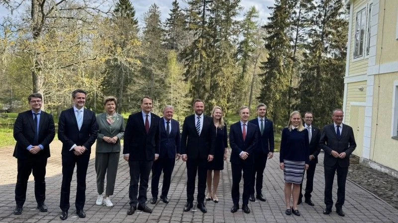 Ministrowie stoją przed budynkiem, na tle lasu