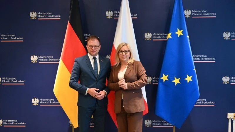 minister i ministra stoją na tle ścianki MKiŚ i flag Niemiec, Polski i UE