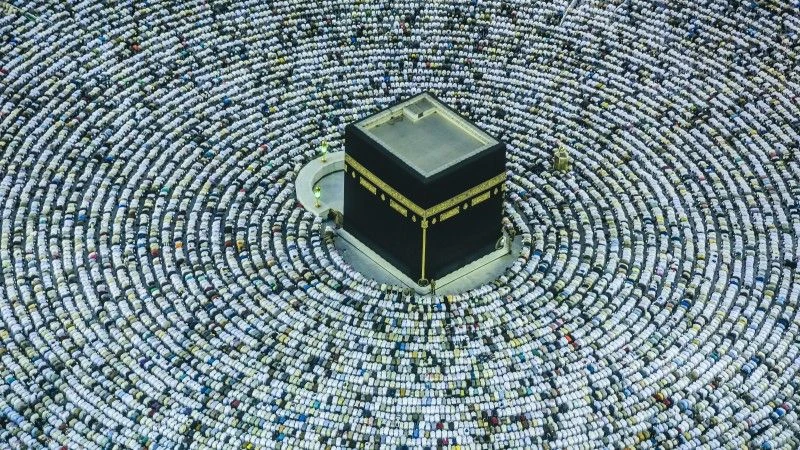 Osoby pochylone w modlitwie wokół świątyni Al-Kaba w Mekce