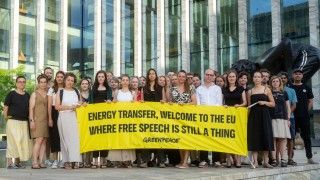ludzie stoją przed budynkiem sądu z transparentem: energy transfer, welcome to the eu, where free speech is still a thing (greenpeace)