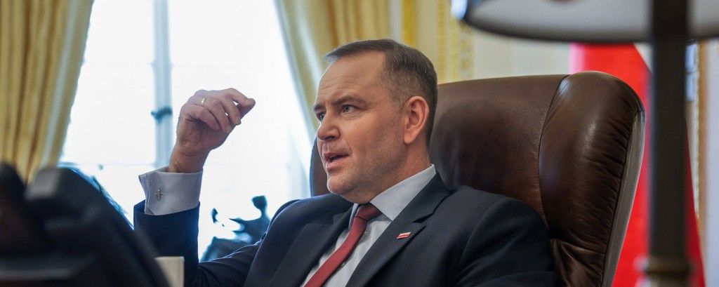 Karol Nawrocki siedzący za biurkiem, rozmawia z kimś, gestykuluje