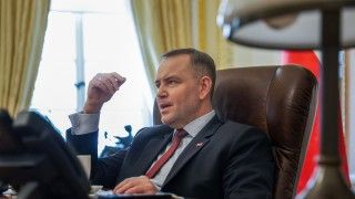 Karol Nawrocki siedzący za biurkiem, rozmawia z kimś, gestykuluje