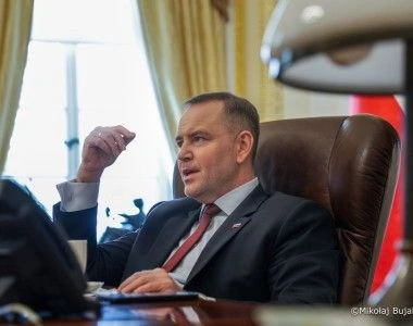 Karol Nawrocki siedzący za biurkiem, rozmawia z kimś, gestykuluje