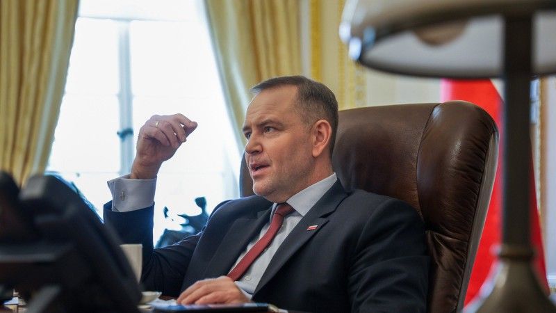 Karol Nawrocki siedzący za biurkiem, rozmawia z kimś, gestykuluje