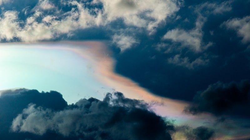 pochmurne niebo przez które przebija się słońce tworząc zjawisko z tęczą na obrzeżach