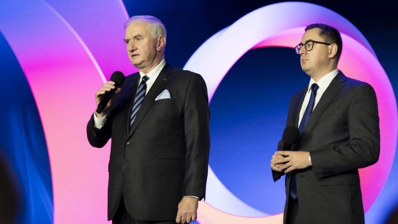 Mężczyźni stoją na scenie z mikrofonami, Marzec przemawia